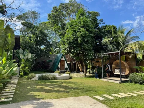 Tropical garden with A-frame cabin and rattan hanging chairs in Silang