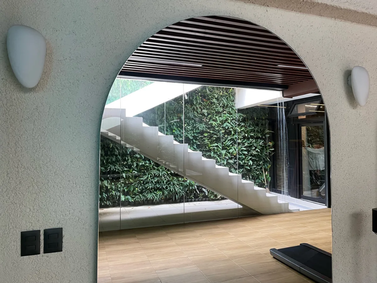 Living green wall behind a floating staircase, seen through an arched opening in a Forbes Park residence