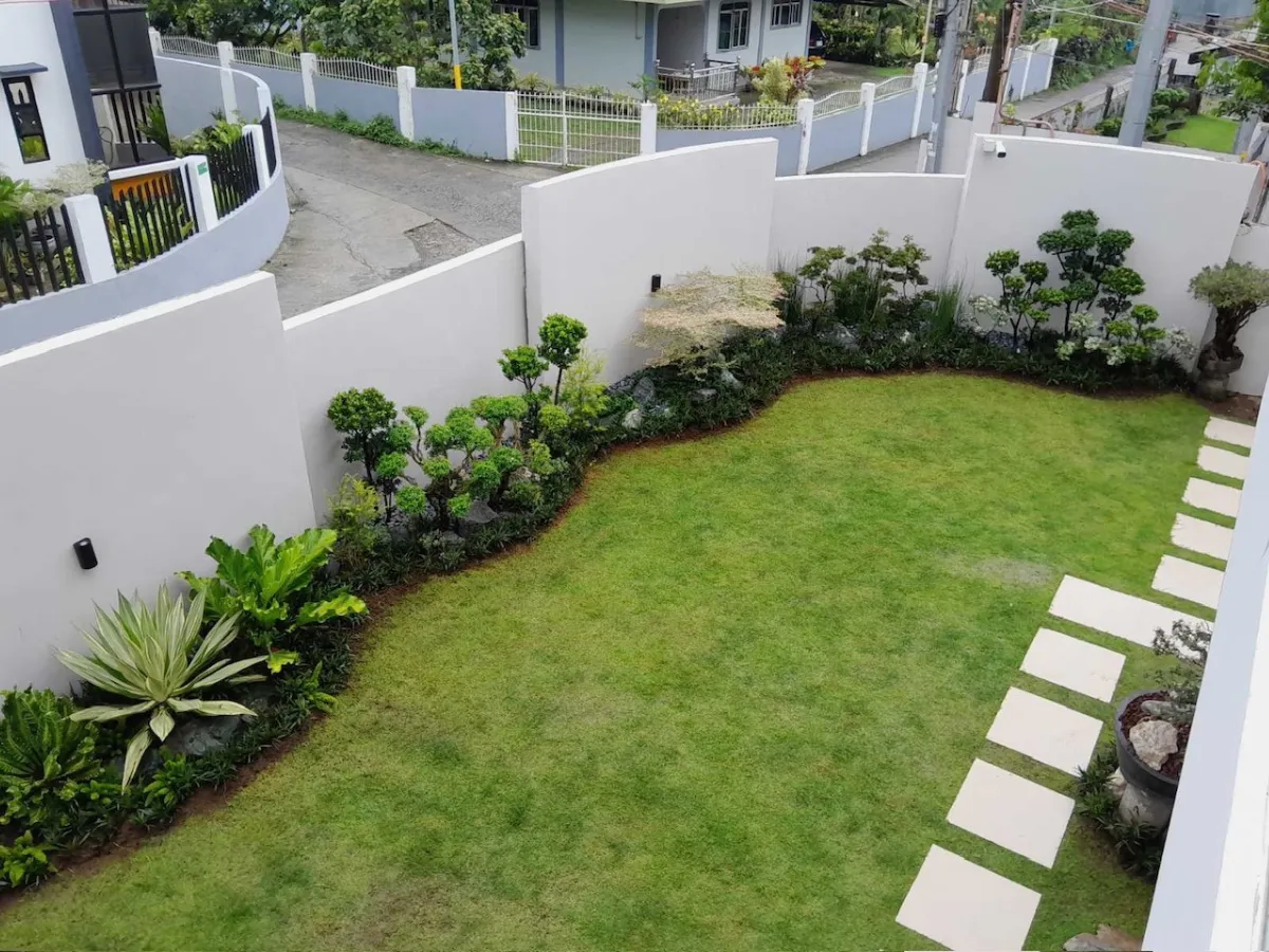 Manicured front yard with topiary shrubs, lawn, and stepping stone path in San Jose Batangas