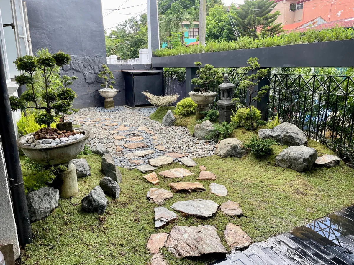 Japanese-inspired garden with stone pathway, bonsai trees, and stone lantern at United Hills Parañaque