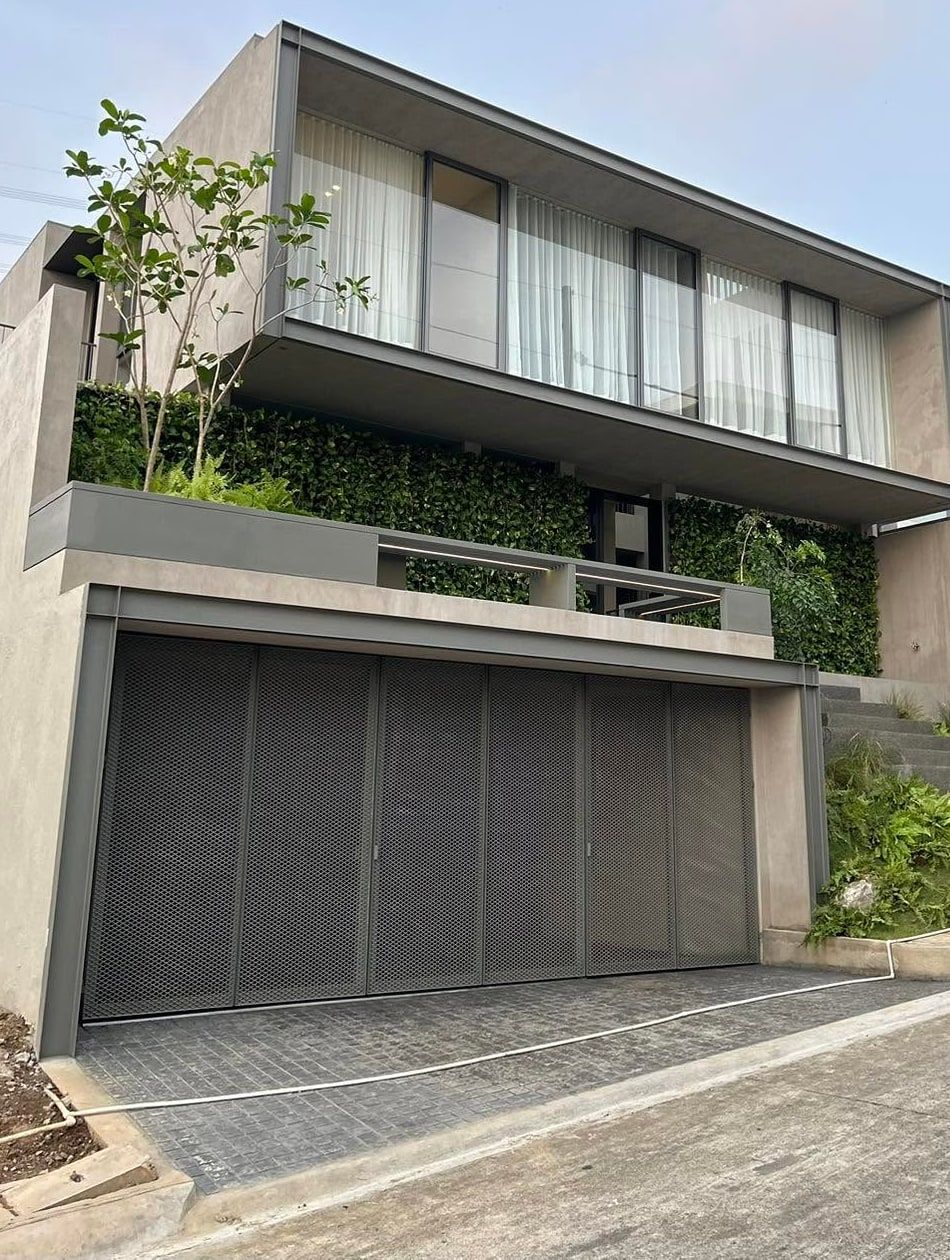 Modern house above a garage, with a vertical garden across the facade and planting on the slope beside the stairs, Taytay, Rizal